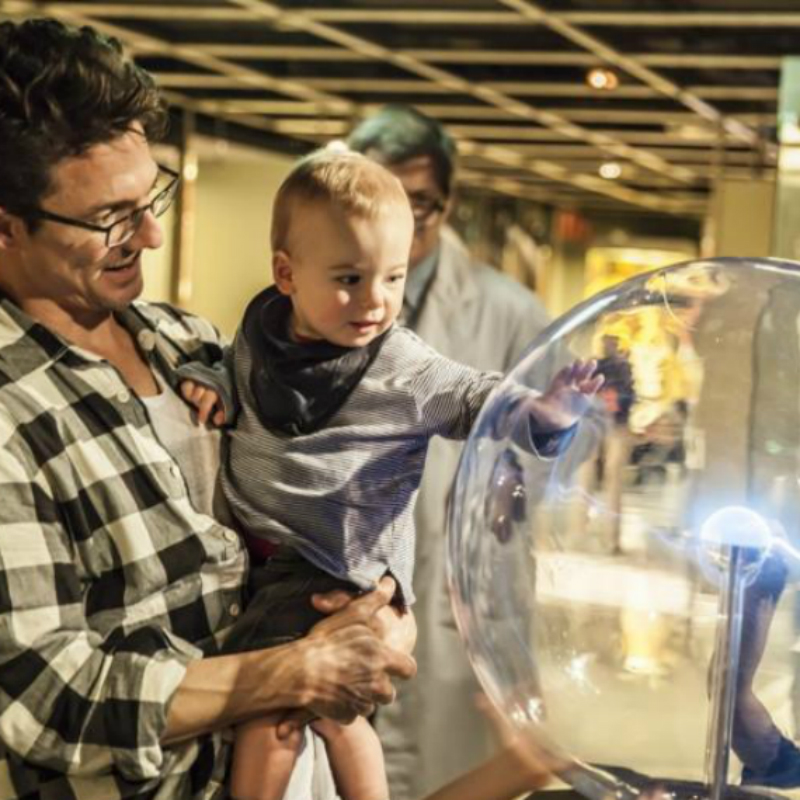 Father-holding-baby-touches-plasma-ball