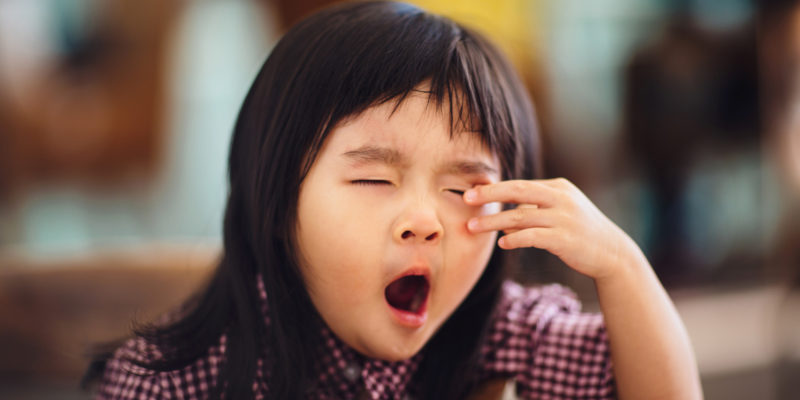 Toddler girl yawning and rubbing eyes 
