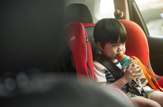 Little boy drinking in a car seat