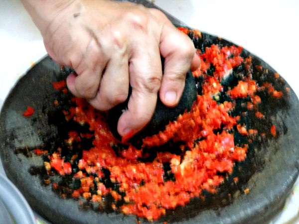 A traditional manner of grinding the chillies, shallots and so on to make sambal is by using a stone mortar and a pestle. (Image Credit) Sakurai Midori. 