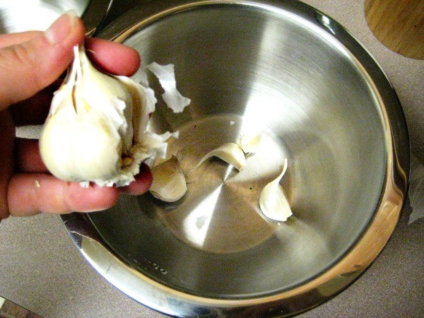 Dropping garlic into a metal mixing bowl. Food Hacks: 5 Secrets to Peeling Garlic