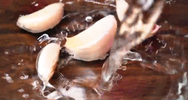 Water pouring on garlic in a bowl. Food Hacks: 5 Secrets to Peeling Garlic