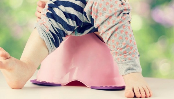 A toddler’s feet in colourful pants straddling potty. Toilet Training your Toddler Fast, using the Malaysian Way