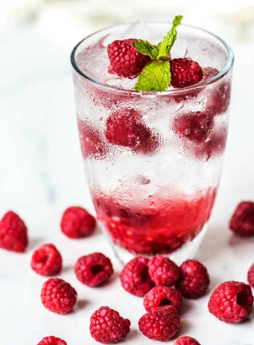 A glass of cold water with red berries. ‘Sitting the Month’