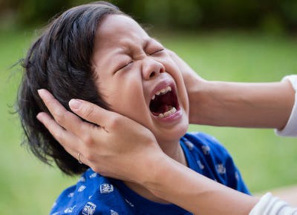 A screaming boy held by hands on his face Is Your Child Affected by the Witching Hour? 10 Ways You Can Banish its Effects 