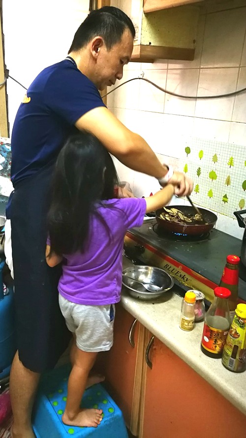 Daughter helping daddy cook dinner for the family.