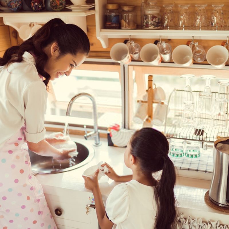 Mother and daughter doing dishes due to single parenting. 