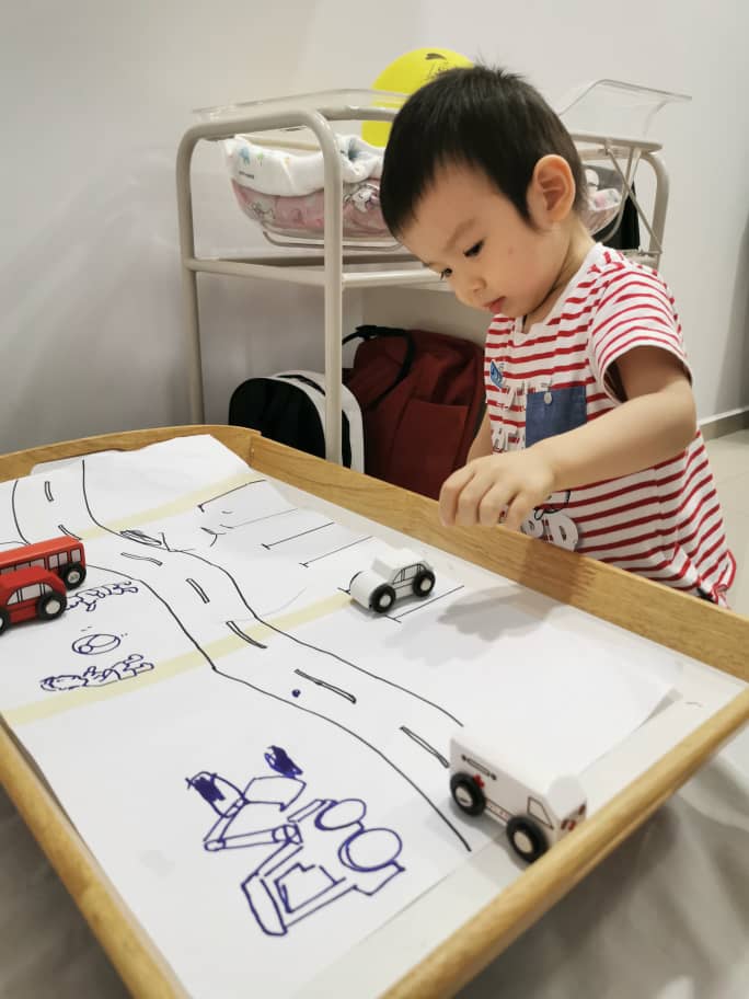 Three pieces of paper and a simple road map attached on a wooden tray keeps Yan Kai happily occupied.