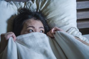 Woman Hiding Under Bedcovers Because of Fear 