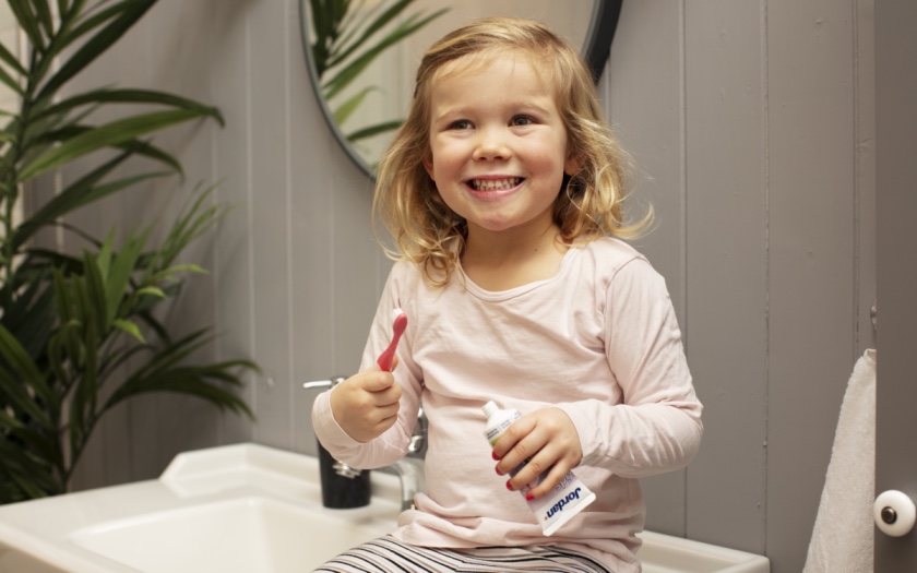 girl holding a toothbrush and jordan toothpaste