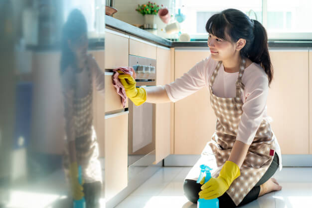 woman wiping and cleaning the kitchen cabinet