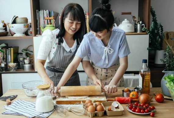 A daughter is helping her mother to knead the dough.