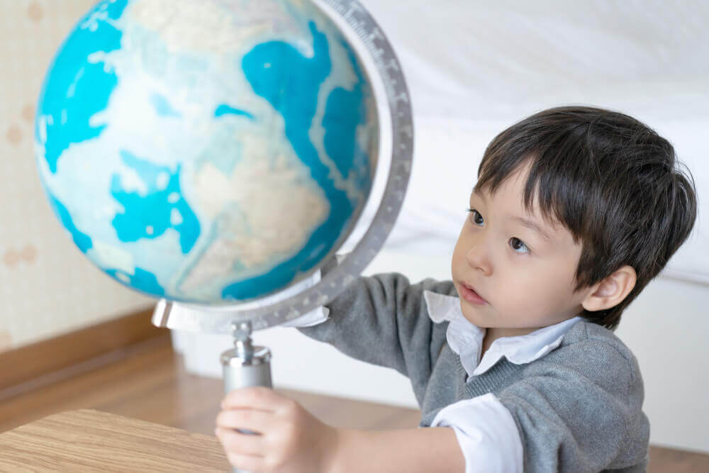 An Asian Boy is looking at the globe.