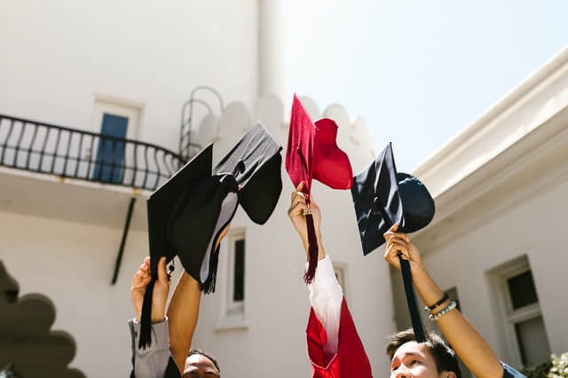Graduates are holding the academic hats high up in the air.