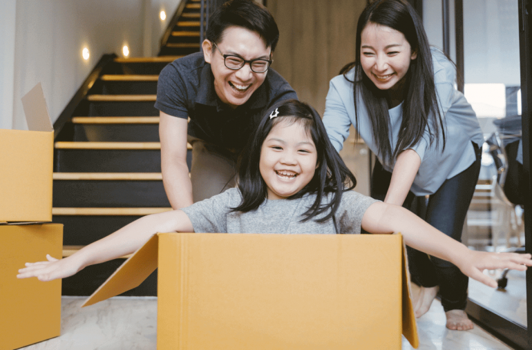 A happy girl is playing in the box with her parents.