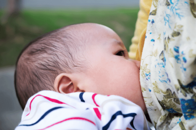 A baby is sucking milk from his mother's breast.