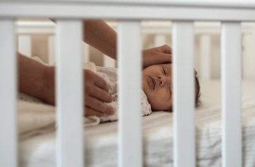 An one-month old baby is sleeping in the cot.