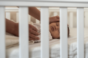 An one-month old baby is sleeping in the cot.