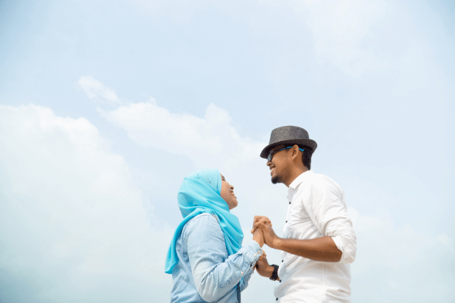 A Malay couple is holding hands while smiling.
