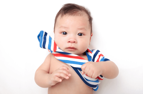 A three-month-old baby is looking at the camera for a photoshot.