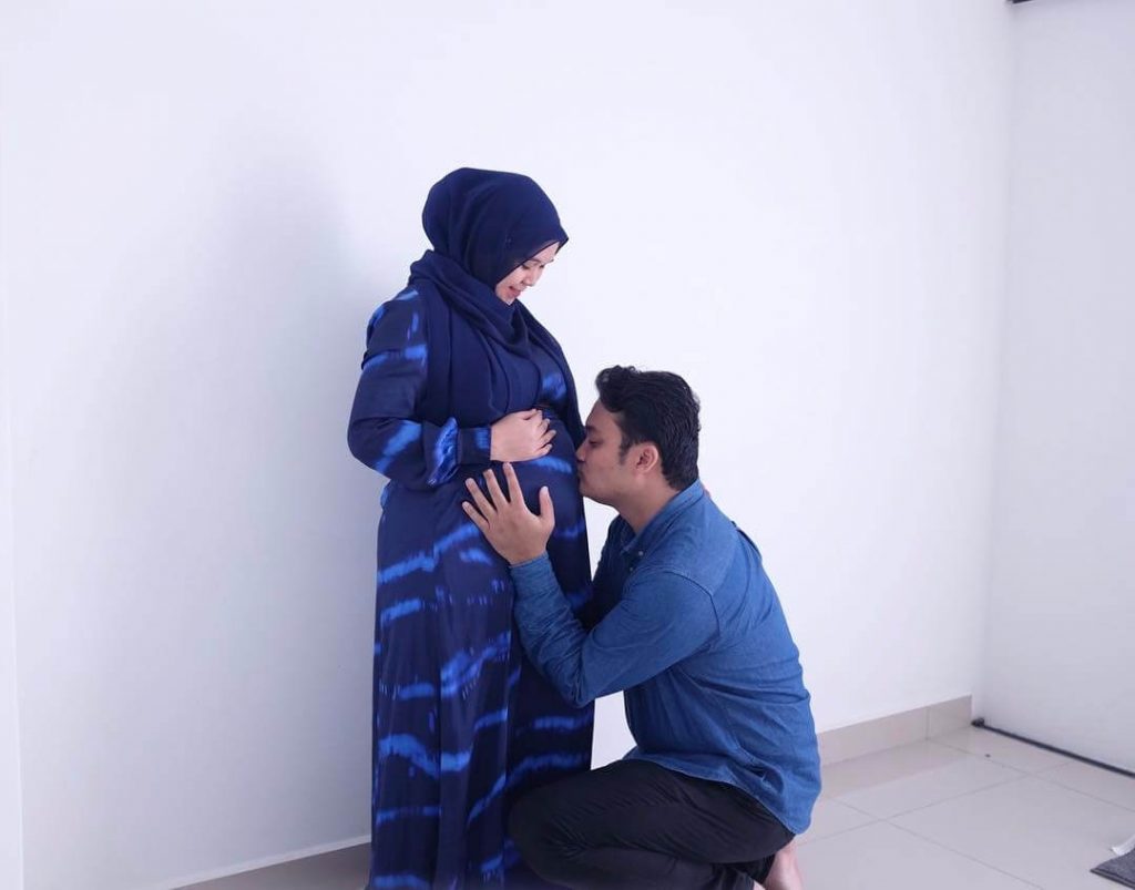 Shafiq is kissing Syafni's belly during her first pregnancy.