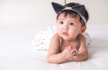 A cute six-month-old is posing with a cat hairband.