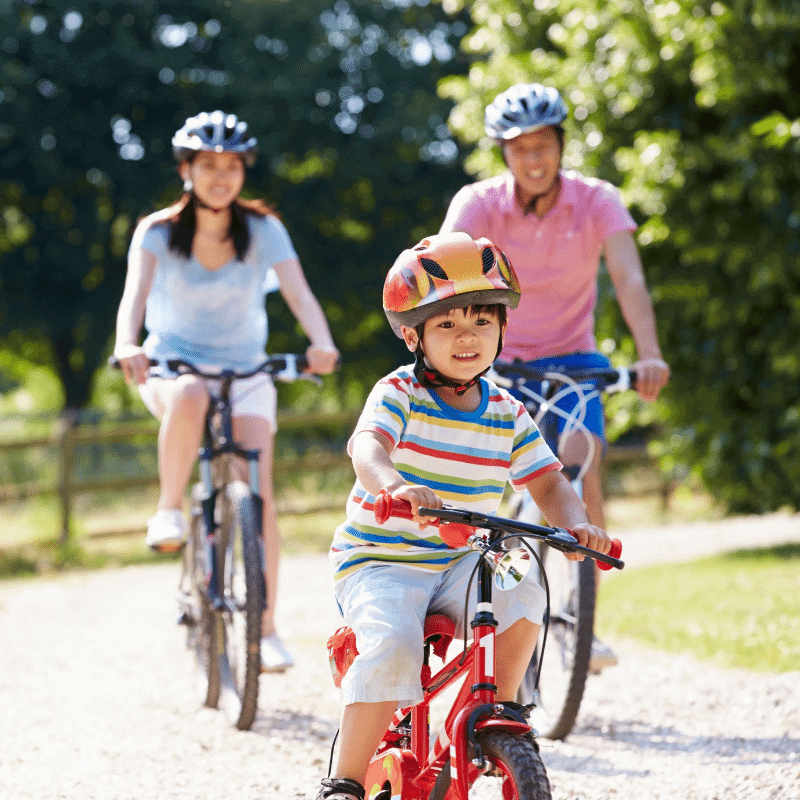A child is cycling happily with his parents.