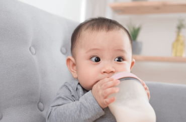 A 9 -month-old is drinking milk from a bottle.