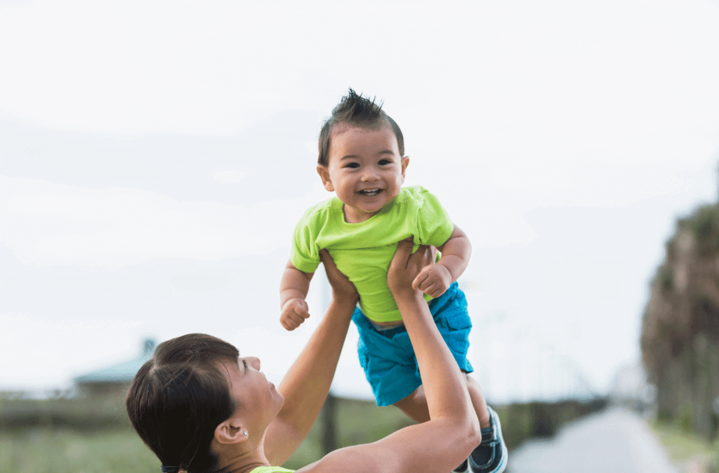 An Asian mother is lifting her 11-month-old baby high in the air.