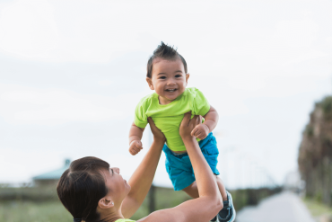 An Asian mother is lifting her 11-month-old baby high in the air.
