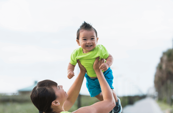 An Asian mother is lifting her 11-month-old baby high in the air.