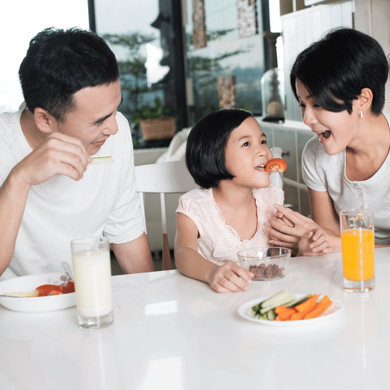 A young Asian family is enjoying healthy snack in the kitchen.
