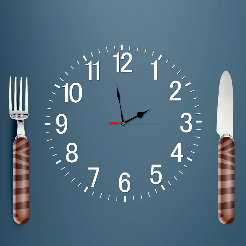 A clock is indicating lunch time concept along with a fork and knife.