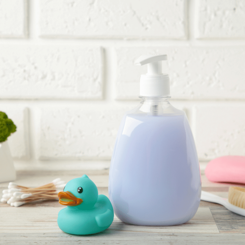 A bottle of body wash is placed next to a blue bath duck.