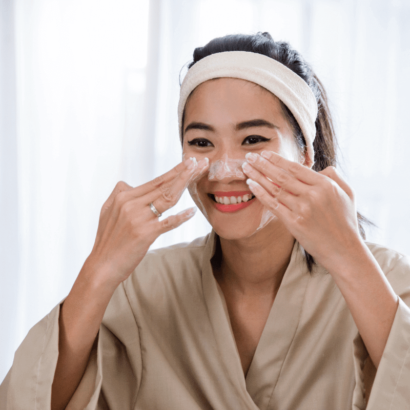 An Asian woman is cleansing her face with cream cleanser.