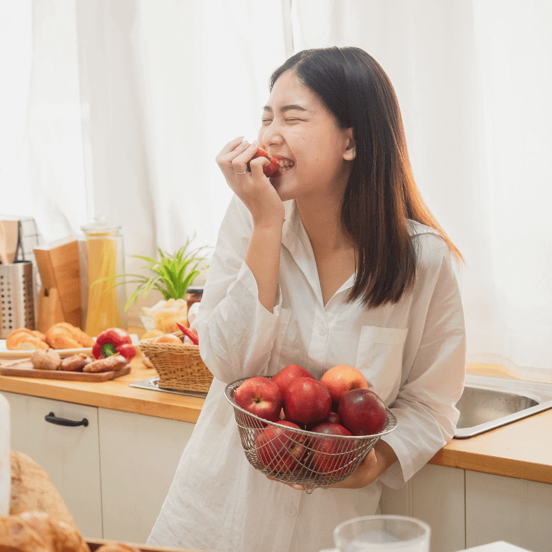 An Asian woman is eating an apple happily.
