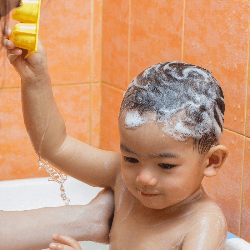 An Asian Toddler is bathing with mum in the bathroom.