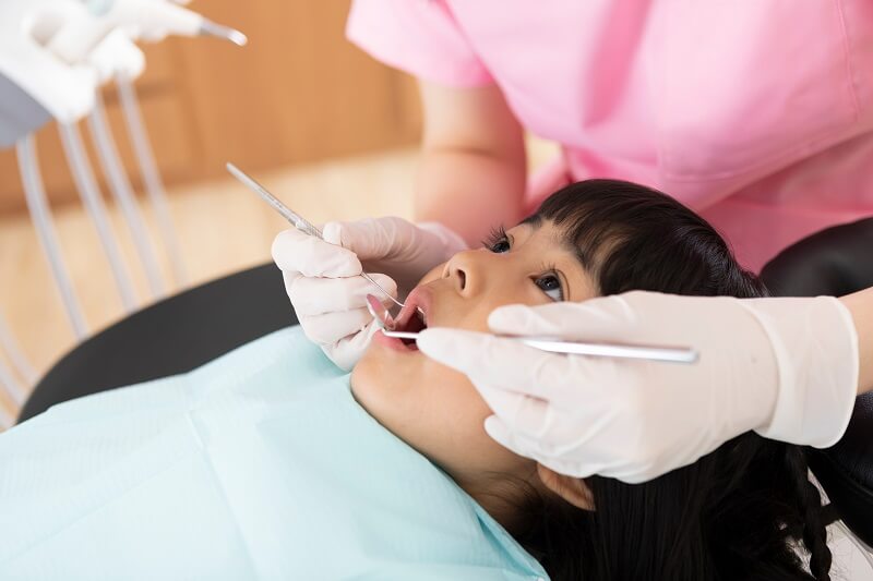 dentists check on a girl's teeth to prevent tooth decay 