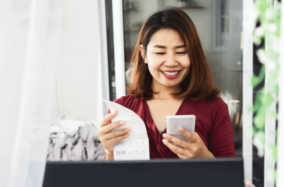 An Asian mother is happily paying the electricity bill with her smartphone.