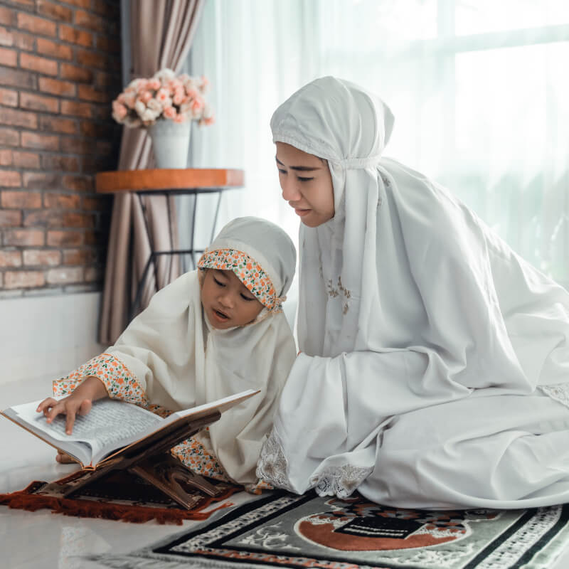 A kid reading Quran with her mum