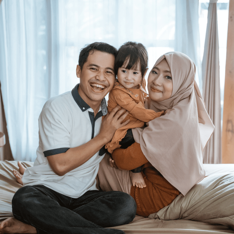 A pair of happy Muslim couple is taking a photo with their daughter.