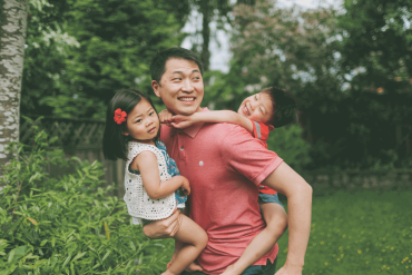 A happy Asian father is hugging his children.