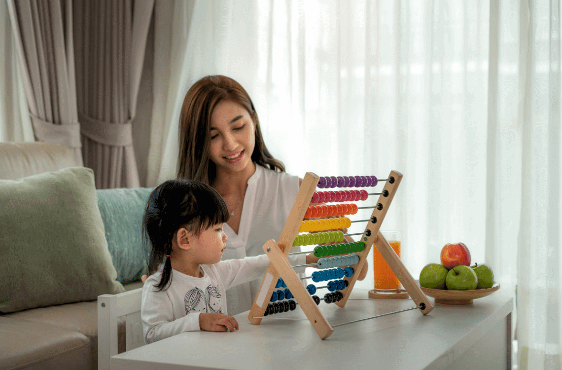 Happy asian mother and daughter playing abacus at home.