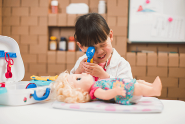 An Asian toddler is having pretend play as a doctor at home.
