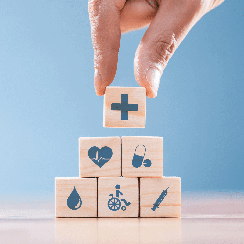 A hand is arranging wooden blocks with healthcare icons.