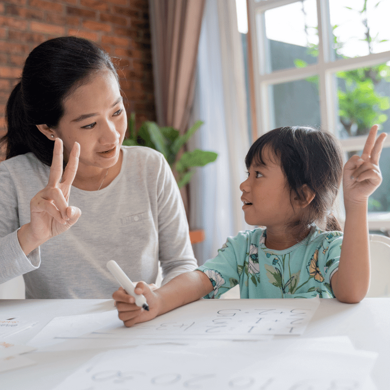 An Asian mum is learning maths with her daughter at home.