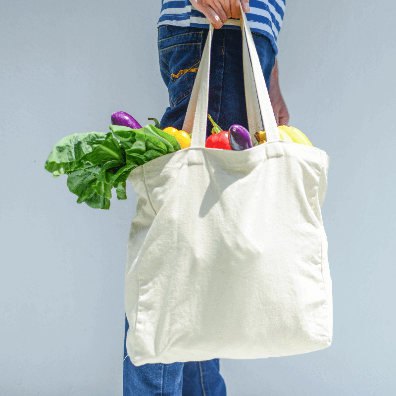 An asian man is carrying a reusable grocery bag.