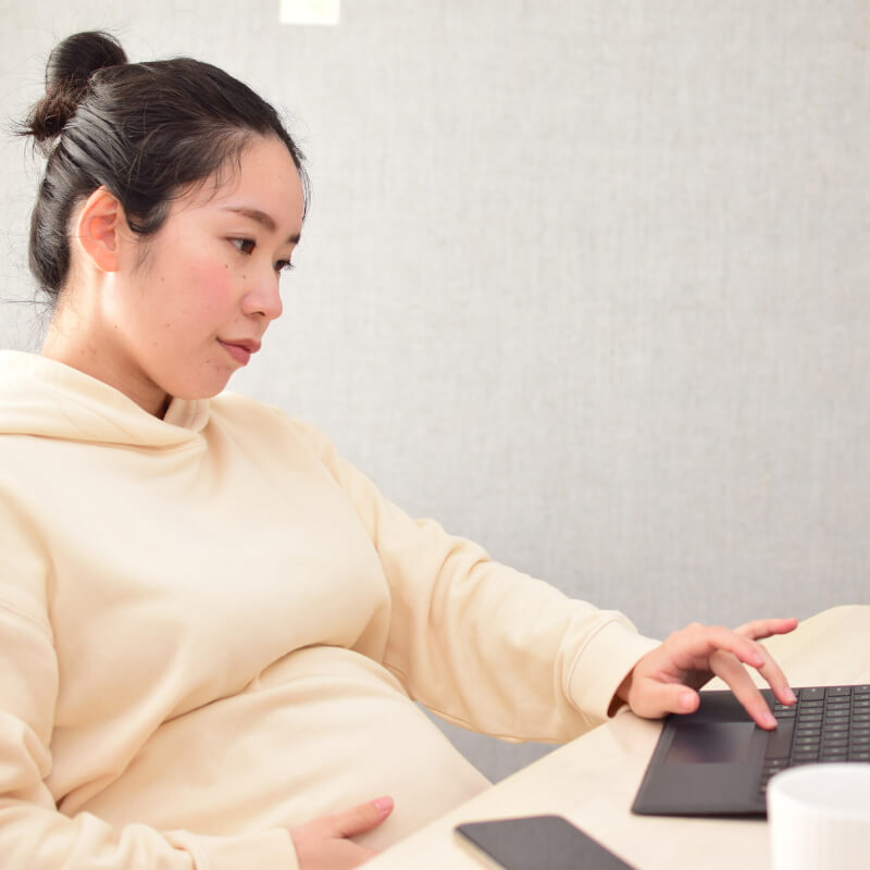 A pregnant mum looking at her laptop