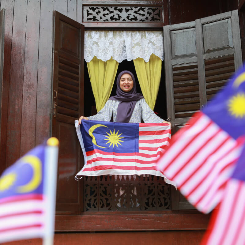 A lady putting up Malaysia flags as Merdeka decor