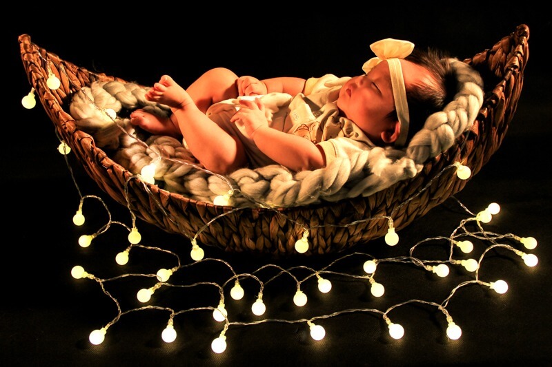 baby photoshoot among fairy lights in basket
